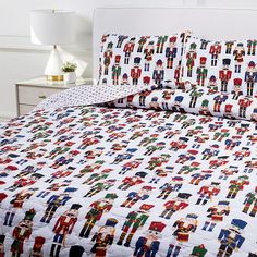 a bed with a white headboard and quilted bedspread covered in toy soldiers