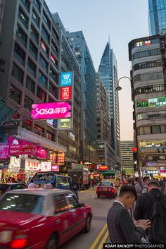 a busy city street filled with lots of tall buildings and cars driving down it's sides