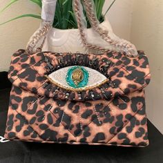 A Sparkle-Encrusted Eye Embellishes A Quilted Shoulder Bag Crafted From Durable Canvas And Featuring A Convertible Chain Strap For Versatile Wear. 7.5"W X 5.12"H X 2.8"D Structured Silhouette With Flat Base For Stability Lined Textile Imported Item #7226924 Designer Rectangular Bag In Leopard Print, Elegant Leopard Print Party Bag, Designer Embellished Shoulder Bag For Everyday Use, Designer Embellished Shoulder Bag, Party Leopard Print Rectangular Bag, Leopard Print Rectangular Party Bag, Evening Bags With Detachable Strap In Leopard Print, Leopard Print Rectangular Party Bags, Luxury Embellished Tote Shoulder Bag