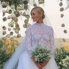 the bride is wearing a white wedding gown and holding a bouquet of flowers in her hand