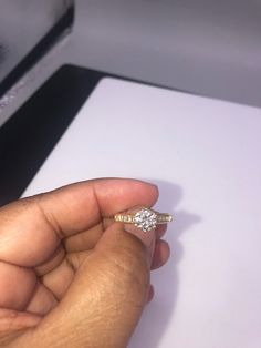 a person holding a ring in their left hand with a diamond on the other side