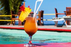 a drink sitting on top of a table next to a swimming pool