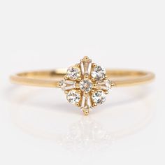 a yellow gold ring with three stones on it's side and the center stone is surrounded by small white diamonds