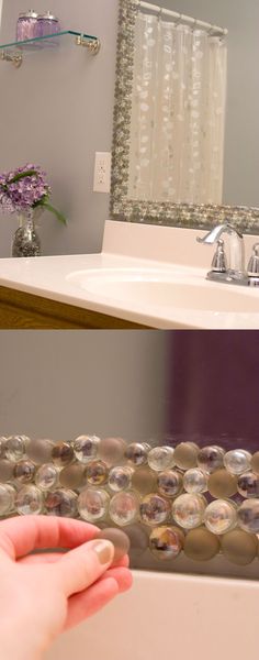 a person's hand is touching the mirror in front of a bathtub with soap bubbles on it