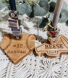 two baseball themed wooden trophies sitting on top of a table next to a bouquet of flowers