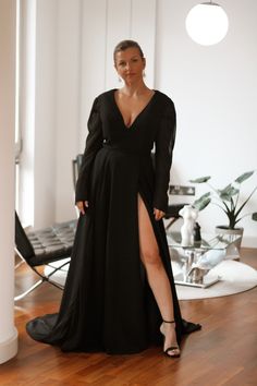 a woman in a black dress standing on a wooden floor