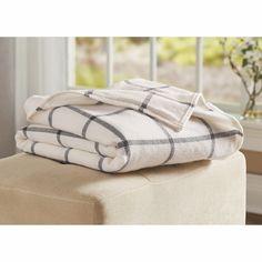 three folded towels sitting on top of a stool in front of a window with windowsills