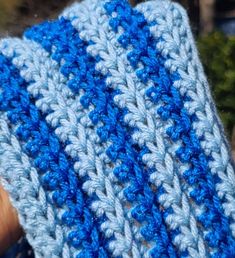 a blue and white crocheted dishcloth being held by someone