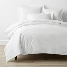 an unmade bed with white sheets and pillows