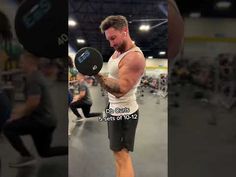 a man holding a kettle while standing on top of a gym floor with other people in the background