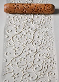 a carved wooden object sitting on top of a white tablecloth covered in swirls