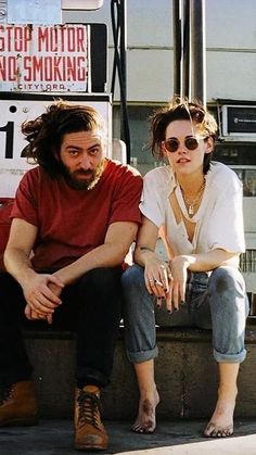 a man and woman sitting on the curb next to each other