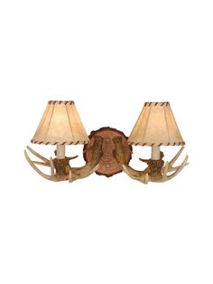 two antler lamps mounted on the side of a wall with shades on each lamp