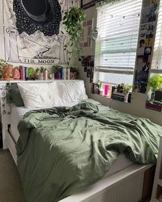 an unmade bed in a bedroom with green sheets and pillows on the headboard