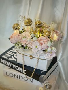 a white box with pink flowers and gold ornaments on top of it next to a pair of glasses