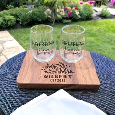 two glasses sitting on top of a wooden cutting board