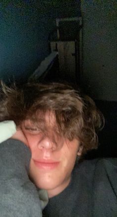 a young man is holding his head against the back of a couch in a dark room