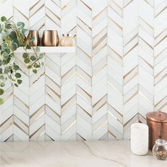 a kitchen counter with gold and white tiles on the backsplash, potted plant next to it