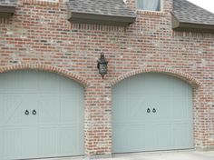 two garage doors are open in front of a brick building with arched doorways on each side