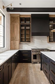 a kitchen with black cabinets and white counter tops, wood flooring and an oven