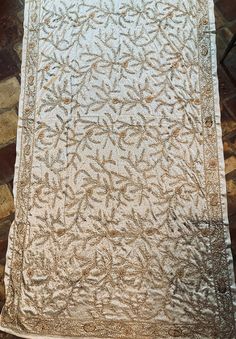 This is an absolutely beautiful hand embroidered and beaded 1980s Indian wedding shawl(?) or throw.  Heavy weight in gold on cream.  Fabulous piece in excellent condition.  Satin ivory material.  Would look stunning as a bed throw.  It does have a few pulled threads but they are barely noticeable and a small area of tarnish on the beads as photographed but still stunning.  It measures 114 centimetres wide by 220 centimetres. Traditional Cream Fabric With Gold Embroidery, Festive White Shawl With Intricate Embroidery, Wedding Pashmina Shawl With Intricate Embroidery, Festive Cream Shawl Dupatta, Festive Cream Dupatta Shawl, Intricately Embroidered Wedding Shawl, Intricate Embroidered Shawl For Wedding, Intricate Embroidered Wedding Shawl, White Embroidered Shawl With Intricate Details