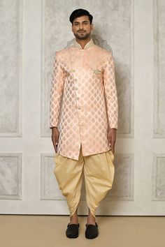 Peach sherwani in asymmetric silhouette with woven swirl patterns and rhinestone embellishments. Comes with dhoti pant.
Components: 2
Pattern: Woven
Type Of Work: Swirl
Neckline: Mandarin Collar
Sleeve Type: Full
Fabric: Tuxedo Satin, Cotton silk
Color: Peach
Other Details: 
Embellished buttons
Closure:
Sherwani: Side placket
Dhoti Pant: Elasticated waistband
Note: Brooch worn by the model is not for sale
Occasion: Mehendi and Puja,Sangeet - Aza Fashions Festive Peach Kurta With Traditional Drape, Peach Traditional Wear For Eid With Traditional Drape, Fitted Peach Traditional Wear For Eid, Traditional Peach Kurta With Traditional Drape, Traditional Peach Kurta With Drape, Fitted Peach Kurta For Festive Occasions, Festive Fitted Peach Kurta, Festive Peach Fitted Kurta, Peach Tuxedo