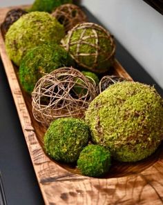 moss covered balls are sitting on a wooden platter