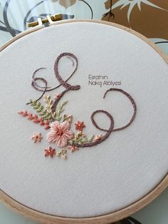 a close up of a embroidery on a wooden hoop with the number six and flowers