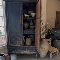 an old cabinet with pots and vases in it