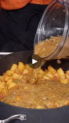 someone pouring something into a pan filled with food