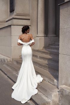 a woman in a white dress is standing on some steps and looking at her back