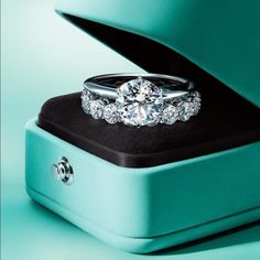 a diamond ring is sitting on top of a box with its lid open and the rest of it's band visible