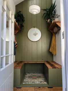 the inside of a bathroom with green walls and wooden steps, potted plants on the wall