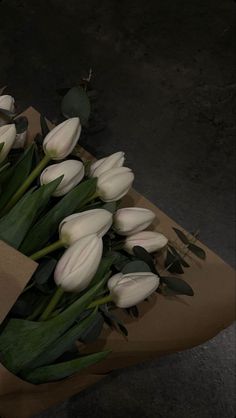 a bouquet of white tulips sitting on top of a brown paper bag