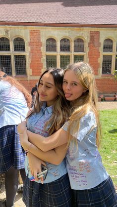 two girls hugging each other in front of a building