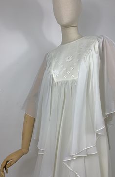 DETAILS - long sheer cape over a sleeveless empire style dress - back zip closure  - floral embroidery yoke - fully lined - poly organza/ viscose  - handmade - dated late 60s early 70s SIZE & MEASURES item laid flat on one side - fits size XS/ S measures available soon CONDITION Excellent vintage condition. White Georgette Dress With Cape Sleeves, Vintage Organza Dress For Spring, Vintage Spring Organza Dress, Spring Vintage Organza Dress, Spring Wedding Dresses With Cape Sleeves, Vintage Summer Dresses With Sheer Sleeves, Summer Vintage Dresses With Sheer Sleeves, Vintage Organza Summer Dress, Summer Dresses With Floral Embroidery And Cape Sleeves