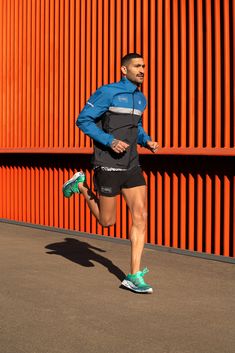 a man running in front of an orange wall with his head turned to the side