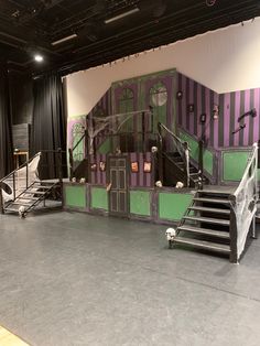 an empty stage with stairs and railings in front of a black curtained wall