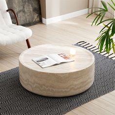 a round coffee table with a candle on it in a living room area next to a chair and rug