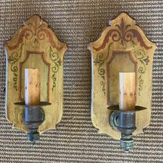 two wooden wall sconces with candles in them on a carpeted floor next to each other