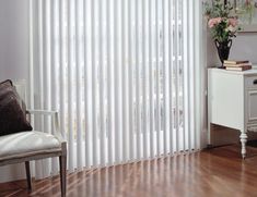 a living room with white vertical blinds and wooden floors