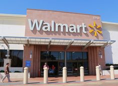 the front entrance to a walmart store with people walking by