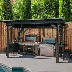 an outdoor kitchen with grills and tables next to a pool