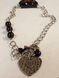 This is a fun brand new with tags set that would make a great gift. The necklace has larger links with a few black beads and a hammered silver tone metal heart pendant. It has a toggle clasp and measures 20" long. The pierced hook earrings have black beads that match the necklace. Metal Heart Charm Dangle Jewelry, Metal Dangle Jewelry With Heart Charm, Metal Beaded Jewelry As Fashion Accessory, Valentine's Day Metal Dangle Necklaces, Double Heart Beads Necklaces For Jewelry Making, Elegant Heart-shaped Jewelry For Jewelry Making, Vintage Heart Charm Dangle Jewelry, Metal Heart Pendant For Jewelry Making, Heart-shaped Metal Jewelry For Gifts