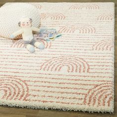 a stuffed animal sitting on top of a rug next to a white and orange pillow