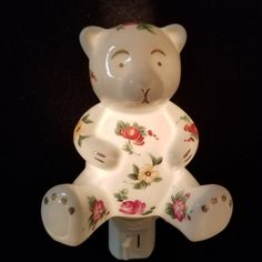 a white bear figurine with flowers on it's body sitting on a black surface