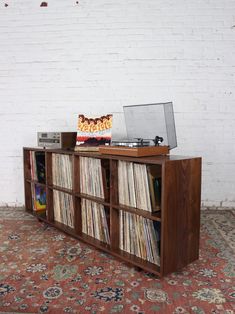 an old record player sitting on top of a wooden shelf next to a white brick wall