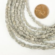 a penny is sitting next to some white bead necklaces on a white surface