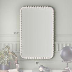 a large white mirror sitting on top of a desk next to a plant and lamp