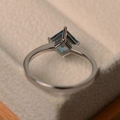 a close up of a ring in a box with a white cloth on the floor